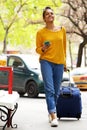 Attractive woman with suitcase and mobile phone on city street Royalty Free Stock Photo