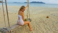 Attractive woman is swinging on a swing. Sexy hot erotic bad girl posing on the beach against the backdrop of the sea Royalty Free Stock Photo