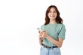 Attractive woman in t-shirt using smartphone messanger, chatting on phone and smiling at camera, reading social media