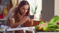 Woman taking picture on smartphone of fruits at kitchen. Lady using mobile phone Royalty Free Stock Photo