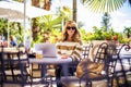 Attractive woman with toothy smile sitting at outdoor cafe and using laptop for work Royalty Free Stock Photo