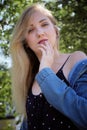 Attractive woman touches her lips. Headshot of blond caucasian woman in park Royalty Free Stock Photo