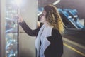 Attractive woman on transit platform using a modern beverage vending machine.Her hand is placed on the dial pad and she Royalty Free Stock Photo