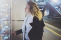 Attractive woman on transit platform using a modern beverage vending machine.Her hand is placed on the dial pad and she Royalty Free Stock Photo