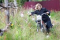 Attractive woman trying to ride the motocross motorcycle in high grass, holding the steering wheel and pushing the bike