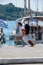 An attractive woman walks along the harbourside pulling a suitcase