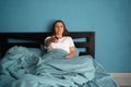Attractive woman watching tv movie series sitting in bed, holding remote control. Girl relaxing watching tv television Royalty Free Stock Photo