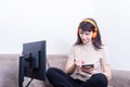 Attractive woman wearing orange headphones looking at a computer monitor and pressing a tablet with her finger Royalty Free Stock Photo