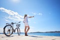 Woman riding a bicycle along stony sidewalk on blue sparkling sea water Royalty Free Stock Photo