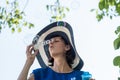 Attractive woman in a wide brimmed sunhat blowing bubbles