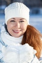 Attractive woman in winter clothing with full guest snow in hands in mittens