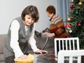 Woman wiping table, elderly mother vacuum cleaning sofa