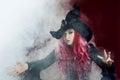 Attractive woman in witches hat with red hair performs magic. Smoke and witchcraft Royalty Free Stock Photo