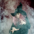 Attractive woman in witches hat with red hair performs magic. Smoke and witchcraft Royalty Free Stock Photo