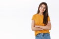 Attractive woman in yellow t-shirt cross hands over chest with self-assured, pleased expression, tilt head and smiling