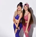 Attractive, young and fit women with long hair wearing sports clothing and knitted hats over a white background