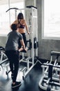 Attractive woman doing exercise with personal trainer at gym