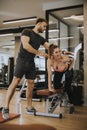 Attractive woman and a personal trainer with weight training at gym Royalty Free Stock Photo