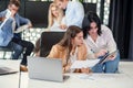 Attractive worker consulting with her office manager and signing financial document at her workplace.