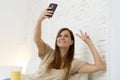 Attractive 30 years old woman playing on home sofa couch taking selfie portrait with mobile phone Royalty Free Stock Photo