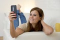 Attractive 30 years old woman playing on home sofa couch taking selfie portrait with mobile phone Royalty Free Stock Photo