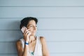 Young adult female in summer dress talking on cell phone while leaning against wood paneled wall Royalty Free Stock Photo