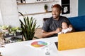 Attractive young african american father holding his little child while sitting at the table with yellow laptop, smiling Royalty Free Stock Photo