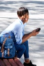 Attractive young african woman sitting on bench outside with mobile phone Royalty Free Stock Photo