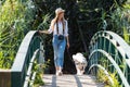 Attractive young amateur photograph woman walking with her dog crossing over a bridge in the park