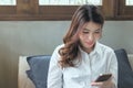 Attractive young Asian business woman looking mobile smart phone in her hands at living room Royalty Free Stock Photo