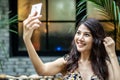 Attractive young asian business woman sitting in cafe and using mobile smartphone selfie happy smiley Royalty Free Stock Photo