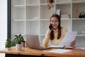 Attractive young asian business woman talking on the mobile phone in the office while working for financial with laptop Royalty Free Stock Photo