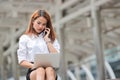 Attractive young Asian business woman using laptop and mobile smart phone for job at outside office. Royalty Free Stock Photo