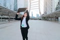 Attractive young Asian business woman walking and raising ring binder at sidewalk of urban city background. Royalty Free Stock Photo