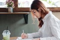 Attractive young Asian business woman writing note on the desk in office. Royalty Free Stock Photo