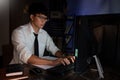 Attractive young asian businessman concentrated working until late overtime on publication at his desk in dark modern office at Royalty Free Stock Photo