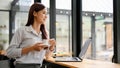 Attractive young asian businesswoman relax sits in the coffee shop, gazing out the window Royalty Free Stock Photo