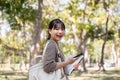 An attractive young Asian female college student with a backpack is walking in the campus park Royalty Free Stock Photo