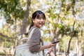 An attractive young Asian female college student with a backpack is walking in the campus park Royalty Free Stock Photo