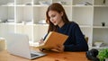 An attractive young Asian female college student making notes on her book Royalty Free Stock Photo