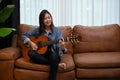 Attractive Asian female playing her classic guitar in the living room Royalty Free Stock Photo