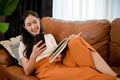 Attractive young Asian female using her smartphone while relaxing on her comfortable sofa Royalty Free Stock Photo