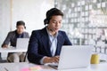 Attractive young asian male call center agent in headset consulting client. Customer service team support concept Royalty Free Stock Photo