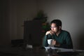Attractive young asian man drinking coffee sitting on desk table looking at laptop computer in dark late night working feeling Royalty Free Stock Photo
