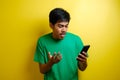 Attractive young asian man reading texting chatting on his phone, bad news, sad crying expression Royalty Free Stock Photo