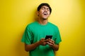 Attractive young asian man reading texting chatting on his phone, bad news, sad crying expression Royalty Free Stock Photo