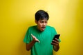 Attractive young asian man reading texting chatting on his phone, bad news, sad crying expression Royalty Free Stock Photo