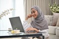 Attractive young Asian Muslim female using laptop in the living room Royalty Free Stock Photo