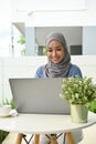 Attractive young Asian Muslim woman remote working at home, using laptop Royalty Free Stock Photo