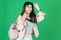 Attractive young Asian tourist girl with bag ready to travel over green isolated background Royalty Free Stock Photo